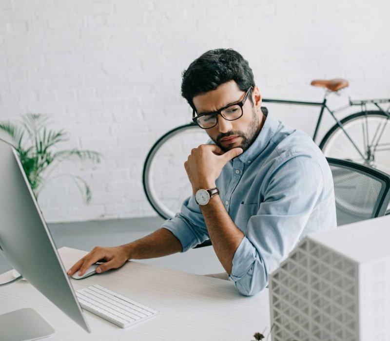 serious-handsome-architect-using-computer-and-looking-at-architecture-model-in-office.jpg